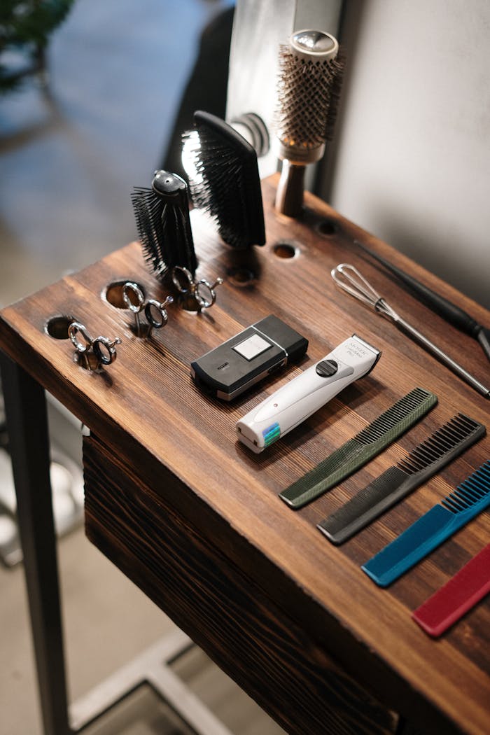 A collection of barber tools neatly arranged on a wooden table, showcasing essential hairdressing equipment.