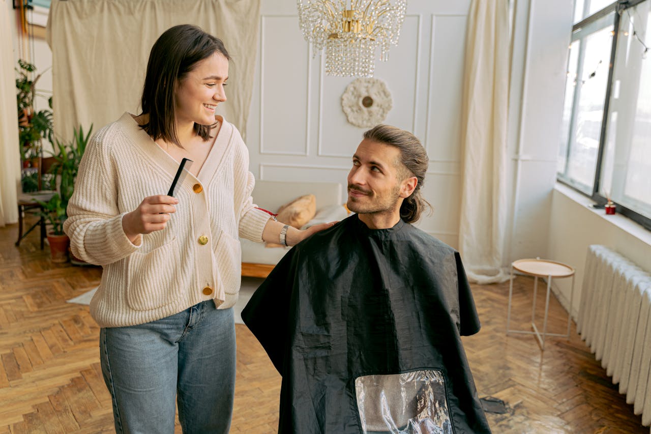 A woman hairdresser styling a man's hair in a luxurious salon, creating a warm, relaxed atmosphere.